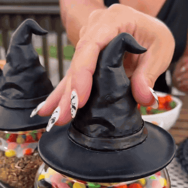 Witch hat candy jar set being shown off at an outdoor Halloween party table