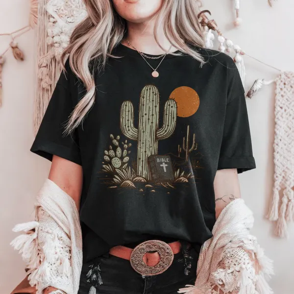 Cactus, With Small Cacti Next To It And A Tombstone With A Cross, With A Cactus Outline And An Orange Circular Sun Western Pattern In The Distance, Casual T-Shirt.